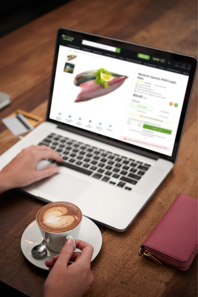 Hands on a laptop showing the mackerel product page next to a cup of coffee